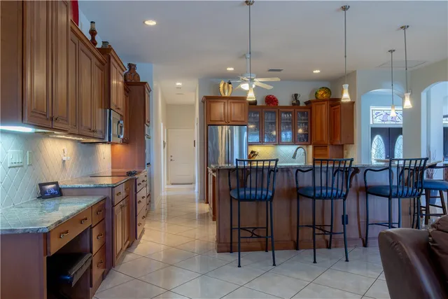 a kitchen with stainless steel appliances granite countertop a refrigerator a sink dishwasher a dining table and chairs with wooden floor