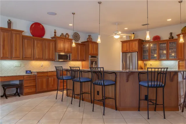 a kitchen with stainless steel appliances kitchen island granite countertop a table chairs and a refrigerator
