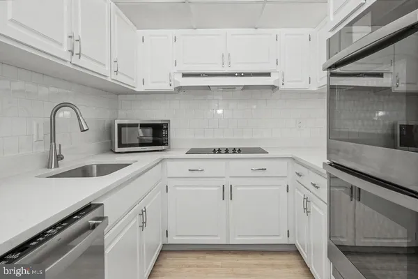 a kitchen with stainless steel appliances granite countertop white cabinets and a sink