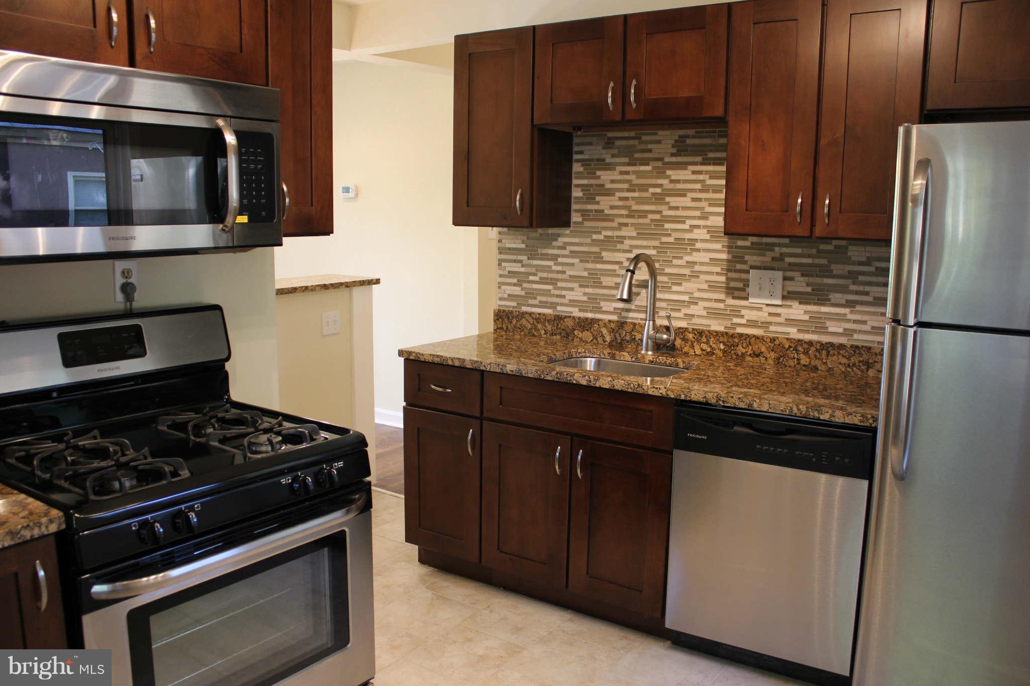 12107 Dewey Road Silver Spring, MD 20906 - Photo 14 of 30 a kitchen with stainless steel appliances wooden cabinets and a stove top oven