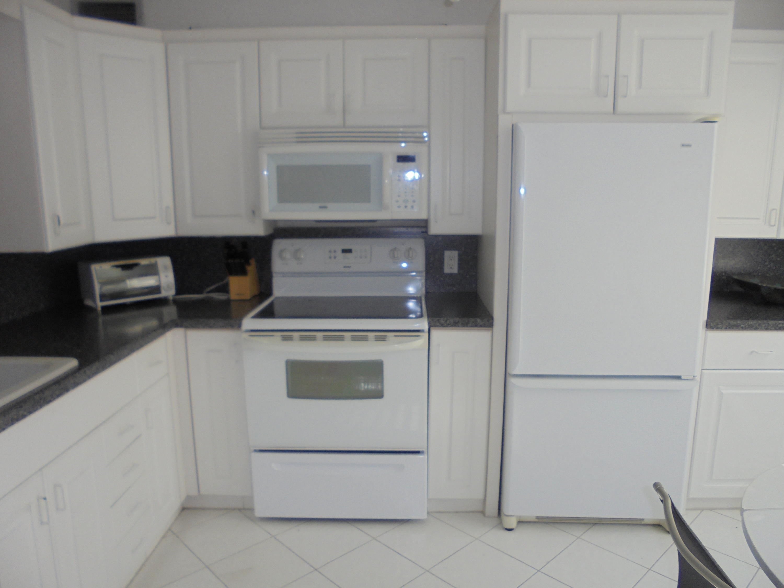 4037 Exeter C Boca Raton, FL 33434 - Photo 4 of 15 a kitchen with white cabinets and white appliances