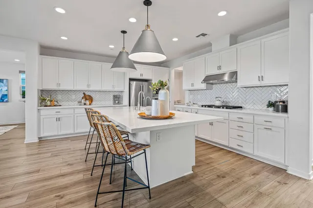 a kitchen with stainless steel appliances a table chairs refrigerator and cabinets