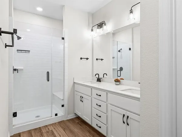 a bathroom with a double vanity sink mirror and shower