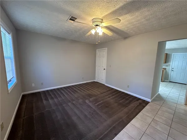 an empty room with wooden floor fan and window