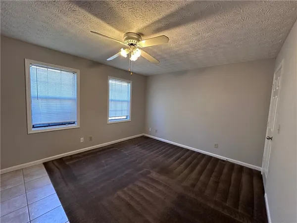 an empty room with wooden floor closet and windows