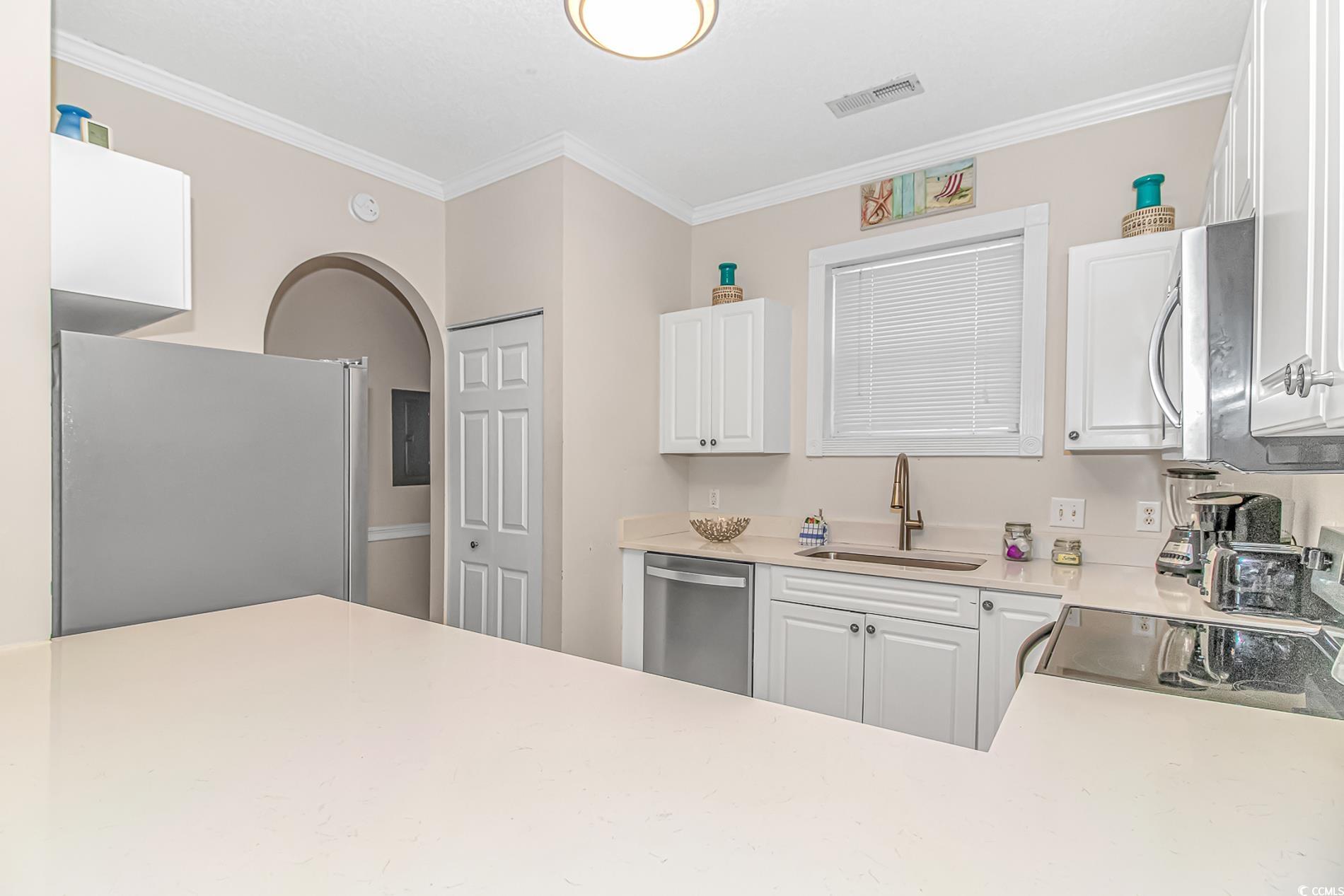 4647 Wild Iris Drive, Unit 303 Myrtle Beach, SC 29577 - Photo 10 of 29 Kitchen with stainless steel appliances, white cabinets, arched walkways, and crown molding
