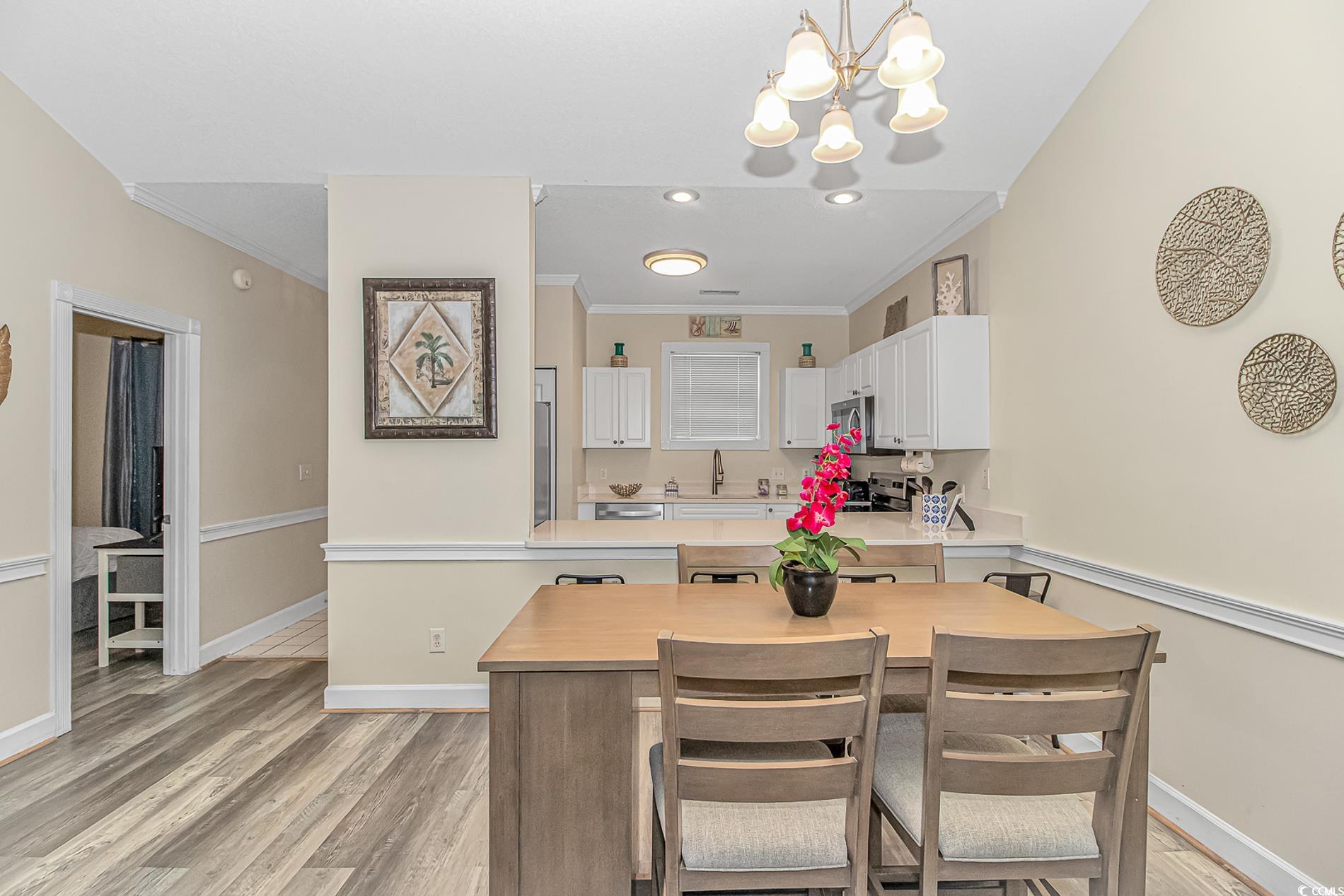 4647 Wild Iris Drive, Unit 303 Myrtle Beach, SC 29577 - Photo 15 of 29 Kitchen with white cabinetry, crown molding, decorative light fixtures, a chandelier, and light wood-style flooring