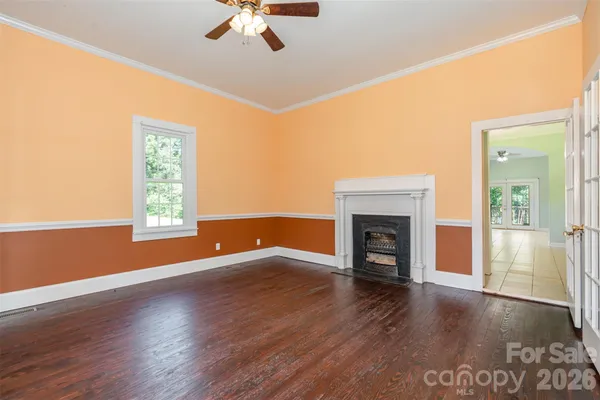 an empty room with windows fireplace and wooden floor