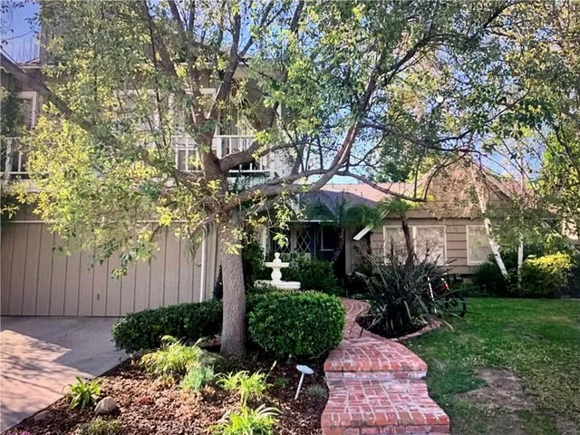 a view of a backyard with potted plants and large tree