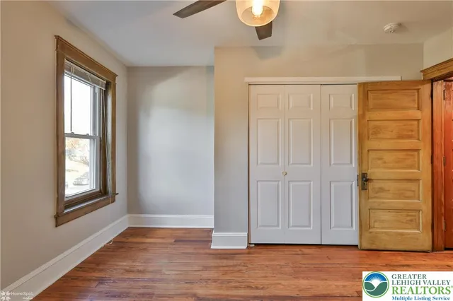 a view of empty room with wooden floor and fan