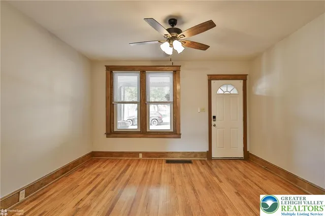 a view of an empty room with wooden floor and a window