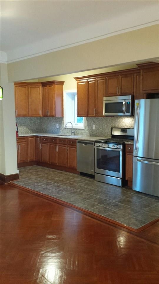 a kitchen with stainless steel appliances wooden floor a stove a sink and a microwave
