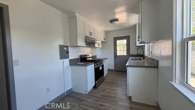 a kitchen with stainless steel appliances granite countertop a refrigerator a sink dishwasher a stove and white countertops with wooden floor