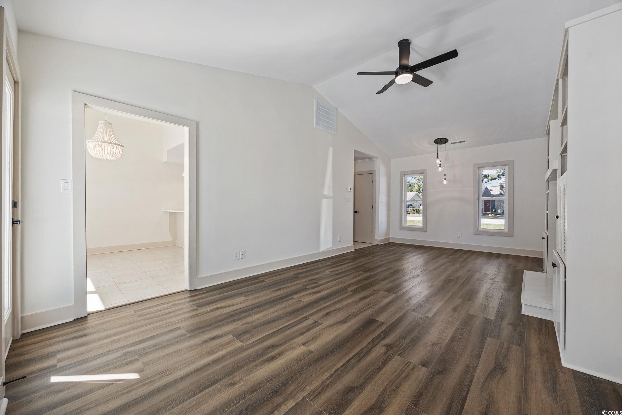 513 Plantation Drive Surfside Beach, SC 29575 - Photo 11 of 44 Unfurnished living room with dark wood-type flooring, vaulted ceiling, and a ceiling fan