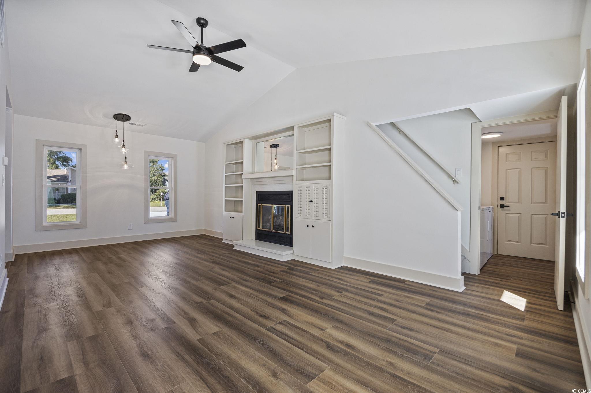 513 Plantation Drive Surfside Beach, SC 29575 - Photo 12 of 44 Unfurnished living room featuring a glass covered fireplace, lofted ceiling, dark wood-style flooring, and ceiling fan