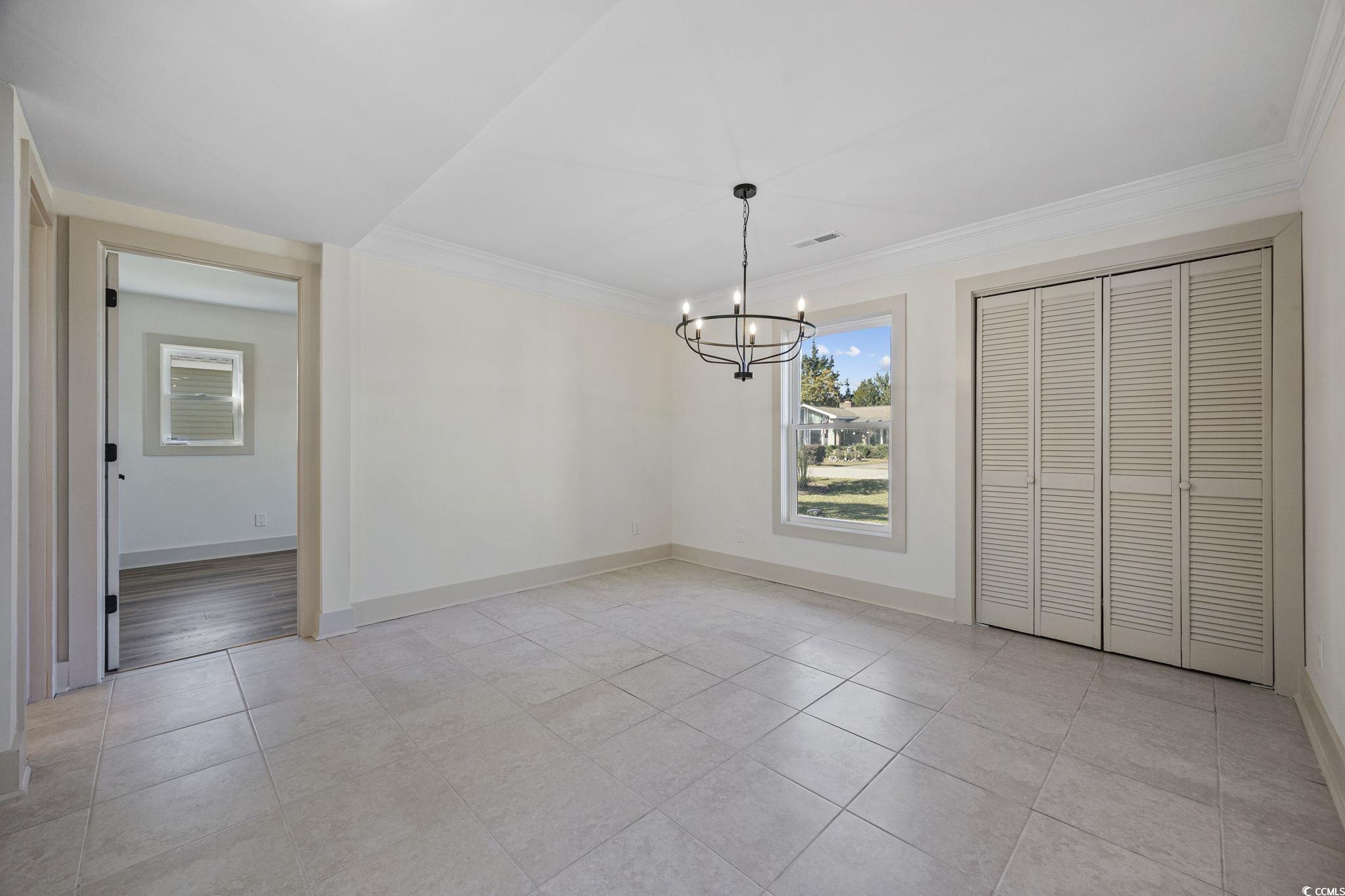 513 Plantation Drive Surfside Beach, SC 29575 - Photo 14 of 44 Unfurnished dining area with ornamental molding, a chandelier, and light tile-patterned flooring. Closet for extra storage.