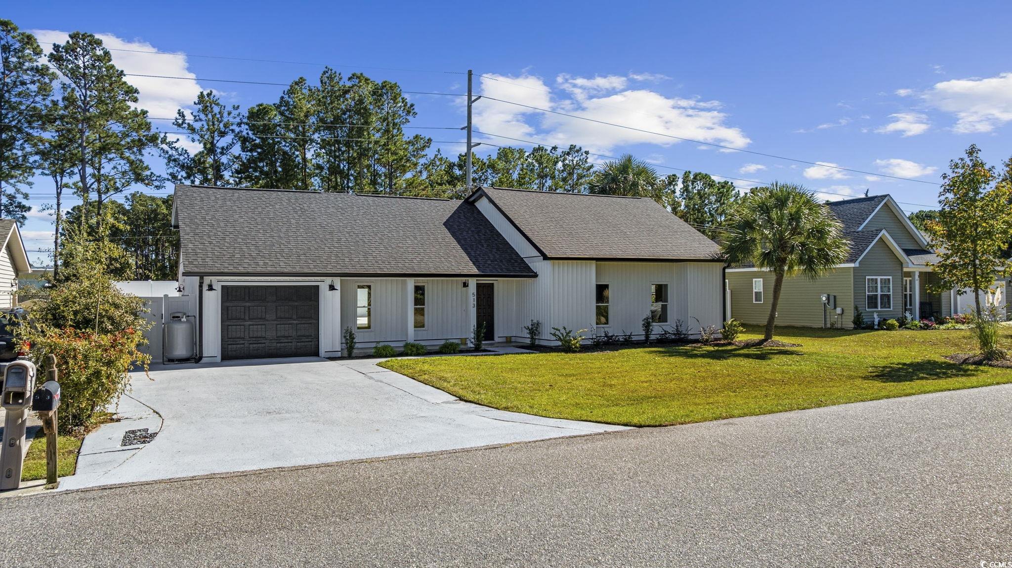 513 Plantation Drive Surfside Beach, SC 29575 - Photo 2 of 44 View of front of home featuring roof with shingles, a front yard, driveway, a garage, and covered porch