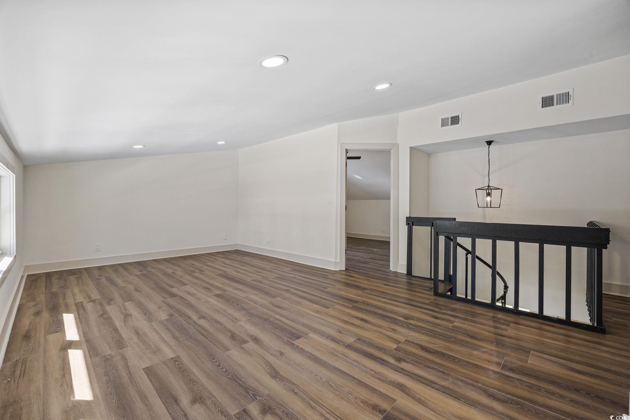 513 Plantation Drive Surfside Beach, SC 29575 - Photo 23 of 44 Spiral stairs lead to a private spare suite featuring dark wood LVP flooring, recessed lighting, and views overlooking the pool and backyard. This upper-level retreat includes a separate bedroom, a spacious office or walk-in closet, and a full bathroom—id