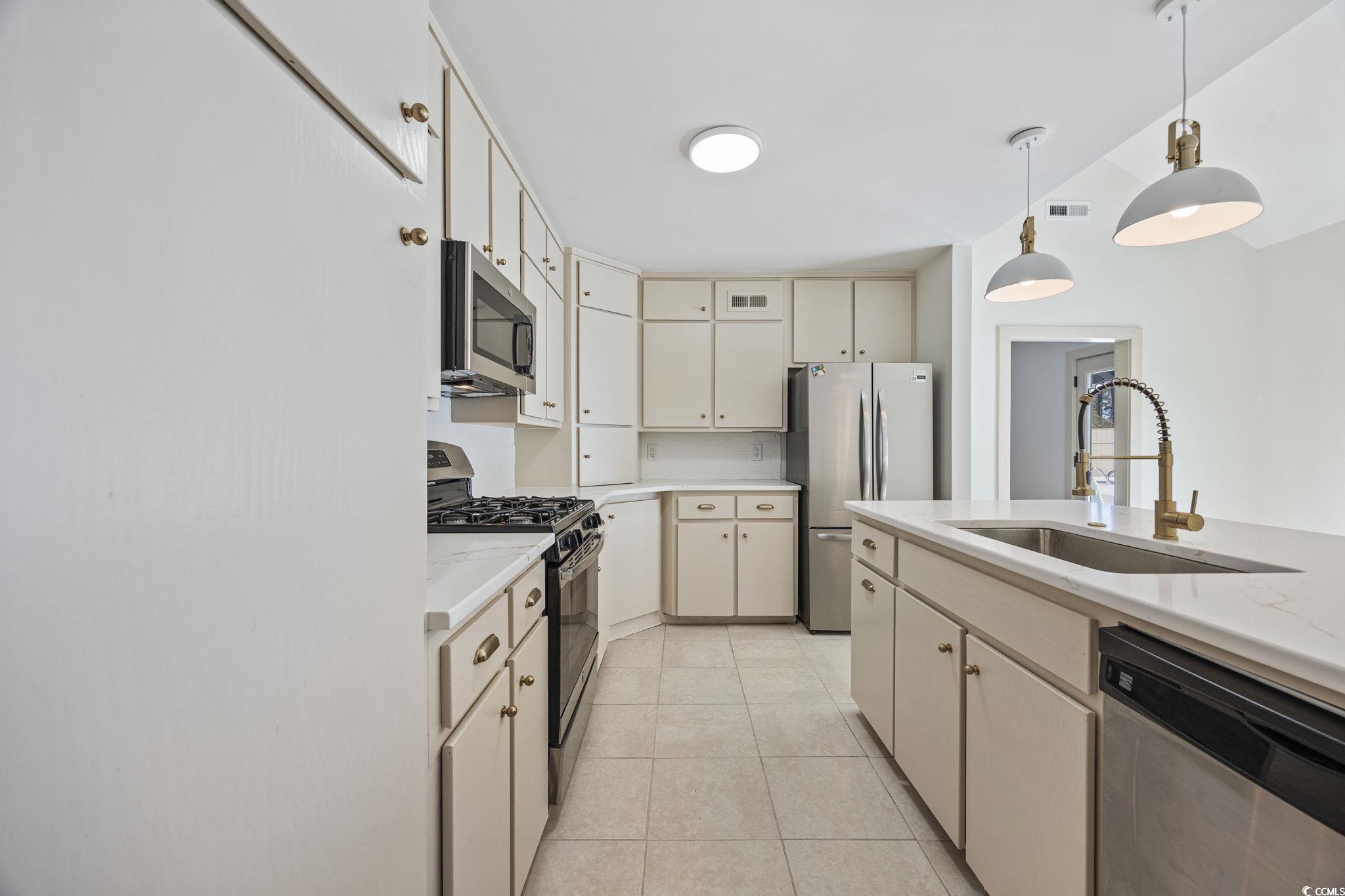 513 Plantation Drive Surfside Beach, SC 29575 - Photo 7 of 44 Kitchen with stainless steel appliances, hanging light fixtures, and light tile patterned floors