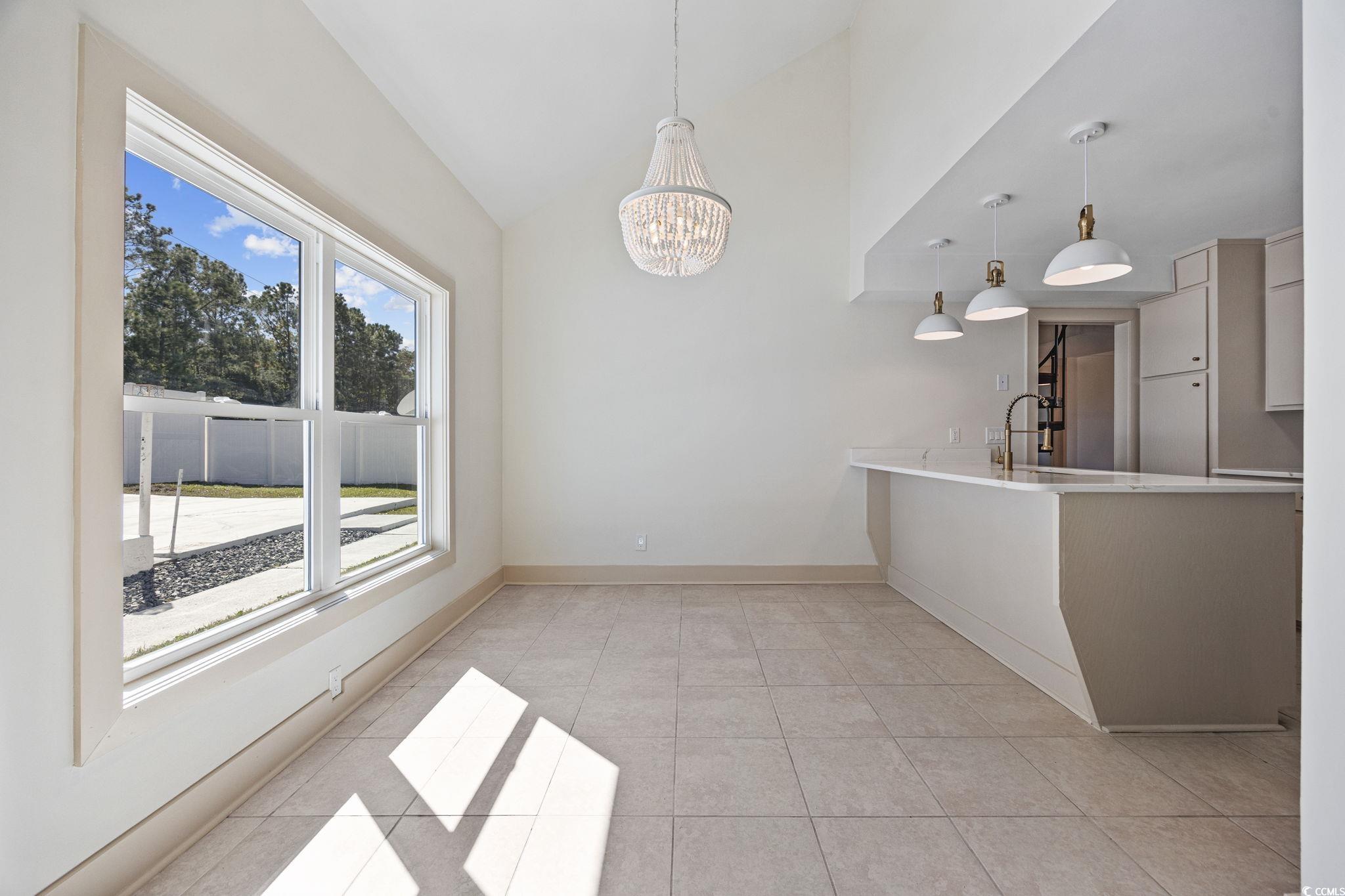 513 Plantation Drive Surfside Beach, SC 29575 - Photo 8 of 44 Unfurnished dining area with a chandelier, light tile patterned floors, and high vaulted ceiling