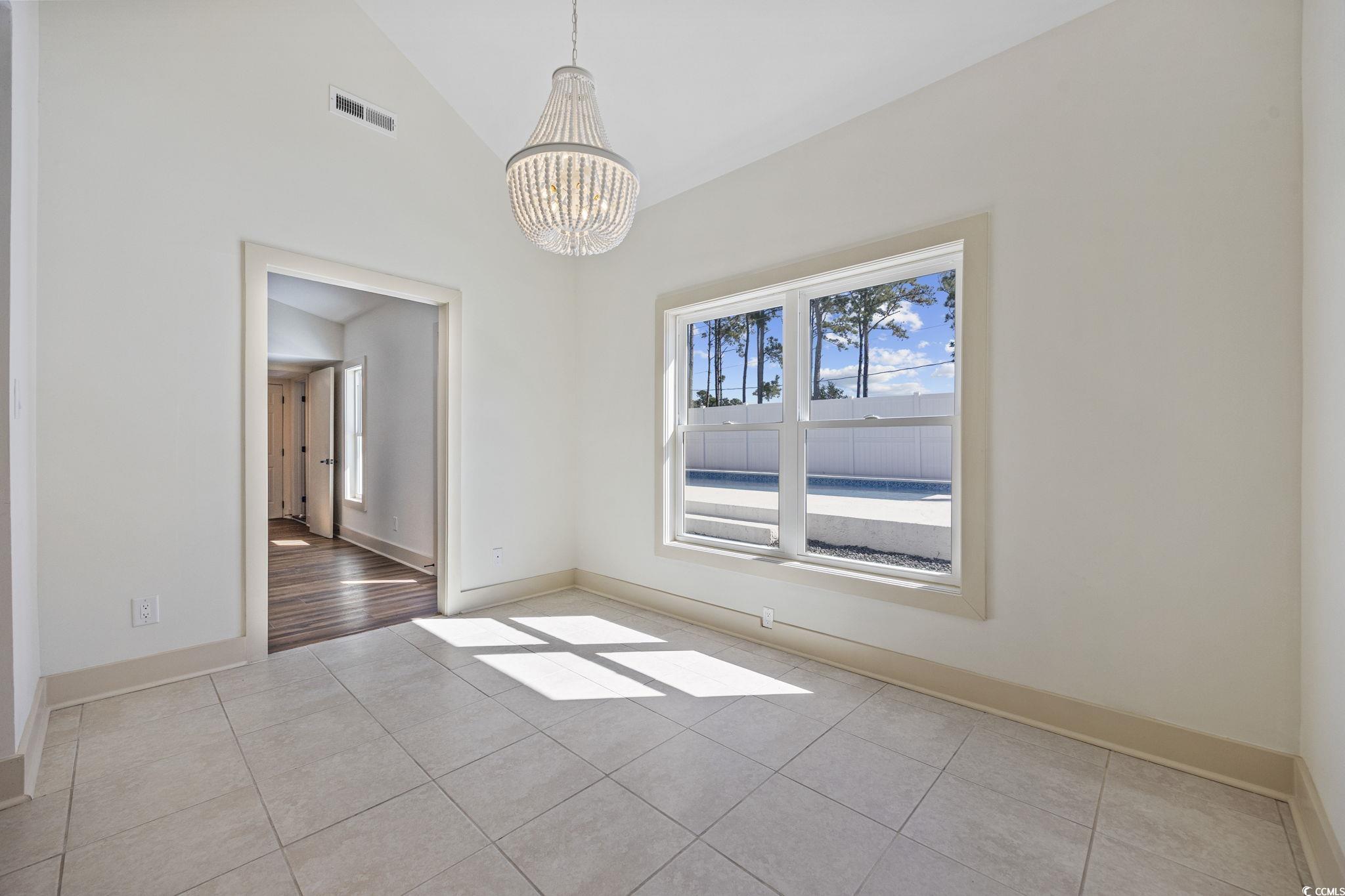 513 Plantation Drive Surfside Beach, SC 29575 - Photo 9 of 44 Unfurnished dining area with light tile patterned floors, a chandelier, and high vaulted ceiling