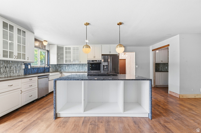 1410 Sumac Drive Logan, UT 84321 - Photo 5 of 28 Kitchen featuring a central island with integrated shelving, granite countertops, and wood-finish flooring