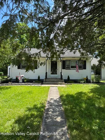 a front view of a house with a big yard and a large tree
