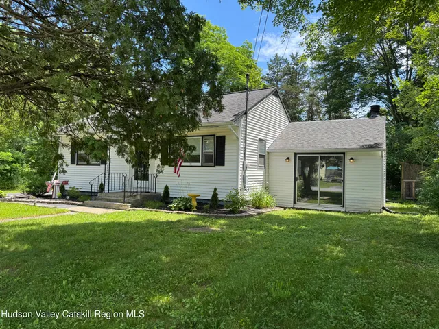 a front view of a house with a yard and trees