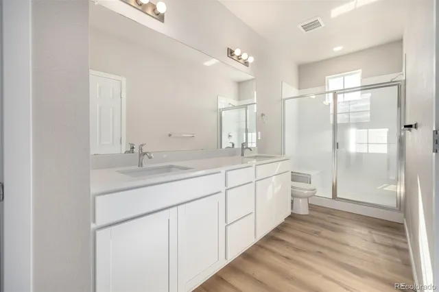 a bathroom with a double vanity sink a toilet and a shower
