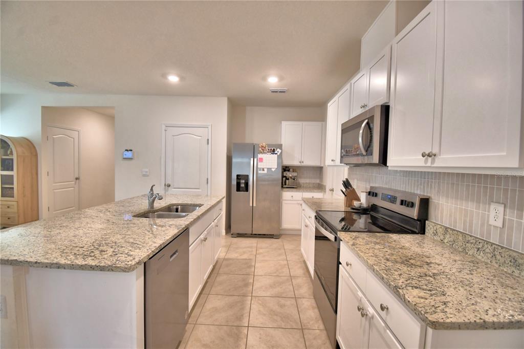 2839 Moulin Road Davenport, FL 33837 - Photo 18 of 75 a kitchen with stainless steel appliances granite countertop a sink stove and refrigerator