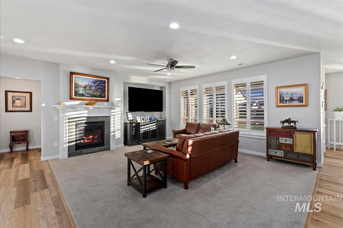 15451 Lutsen Avenue Caldwell, ID 83607 - Photo 7 of 39 Living area featuring a fireplace with a white mantel and dark tile surround, recessed lighting, ceiling fan, and multiple windows with plantation shutters