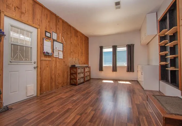 a view of an empty room with window and wooden floor