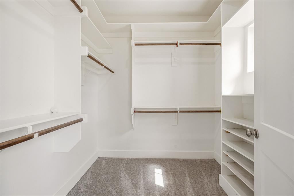 745 North Miller Avenue Stephenville, TX 76401 - Photo 19 of 31 Walk-in closet featuring white built-in shelving, multiple hanging rods, and a gray carpeted floor