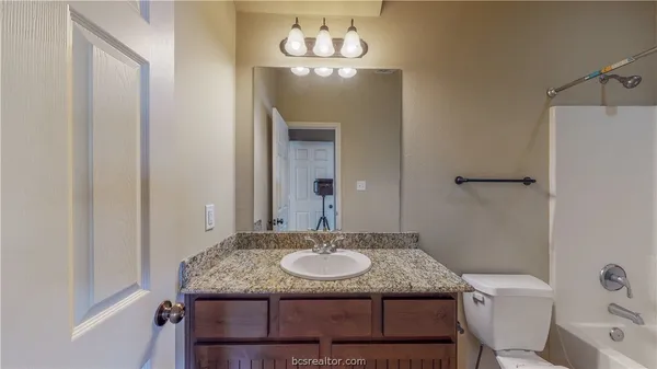a bathroom with a granite countertop sink a mirror and a toilet