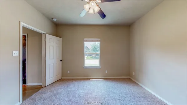 an empty room with a window and a kitchen