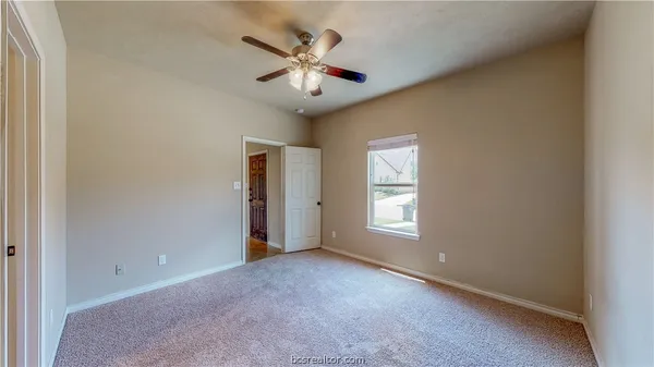 an empty room with chandelier fan and windows
