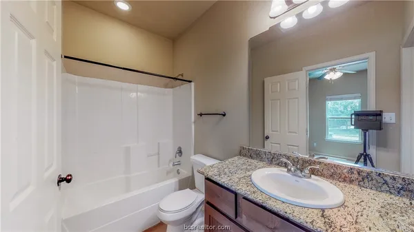 a bathroom with a granite countertop sink toilet and shower