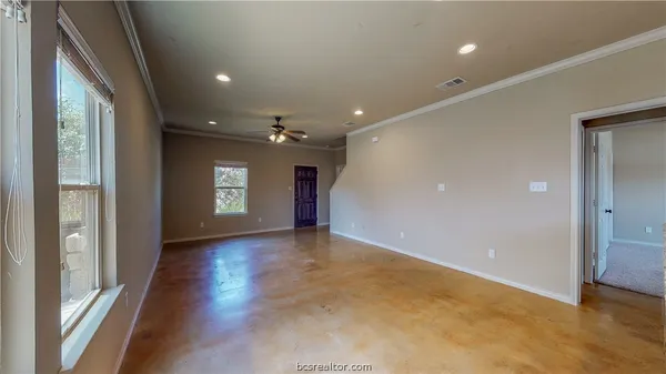 an empty room with wooden floor and windows