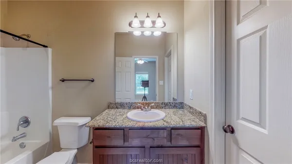 a bathroom with a granite countertop sink a toilet and a mirror