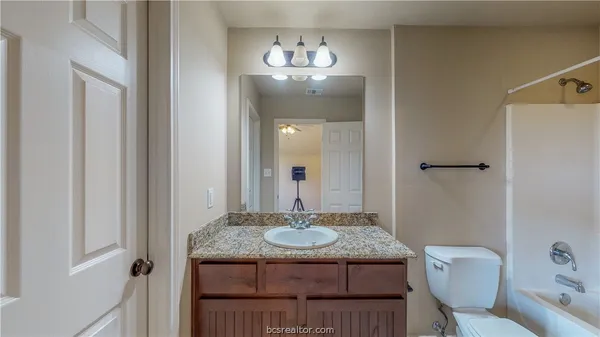 a bathroom with a granite countertop sink a toilet and a mirror