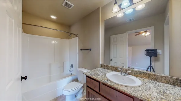 a bathroom with a granite countertop sink toilet and shower