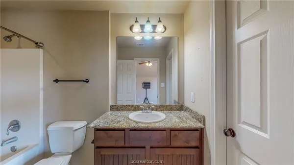 a bathroom with a granite countertop sink a mirror and a toilet
