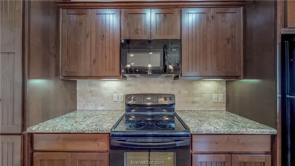 a kitchen with granite countertop a sink stove and cabinets