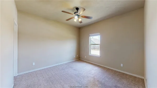 an empty room with window and ceiling fan