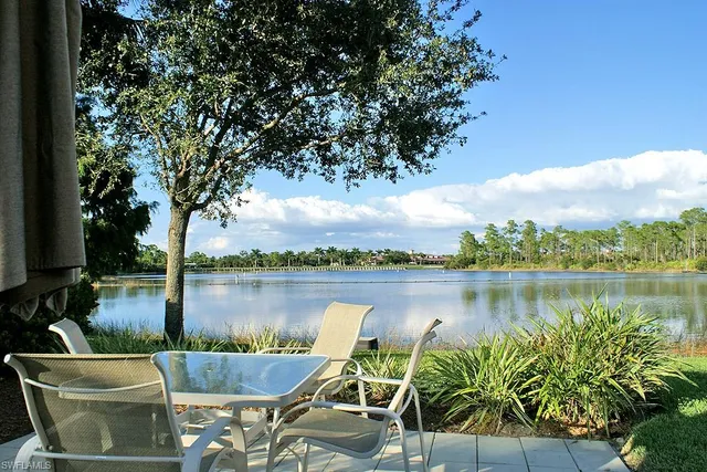 a view of a lake with table and chairs next to a yard