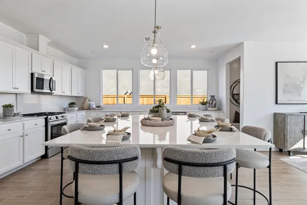 a kitchen with stainless steel appliances granite countertop a sink dishwasher a stove top oven a refrigerator with white cabinets and wooden floor