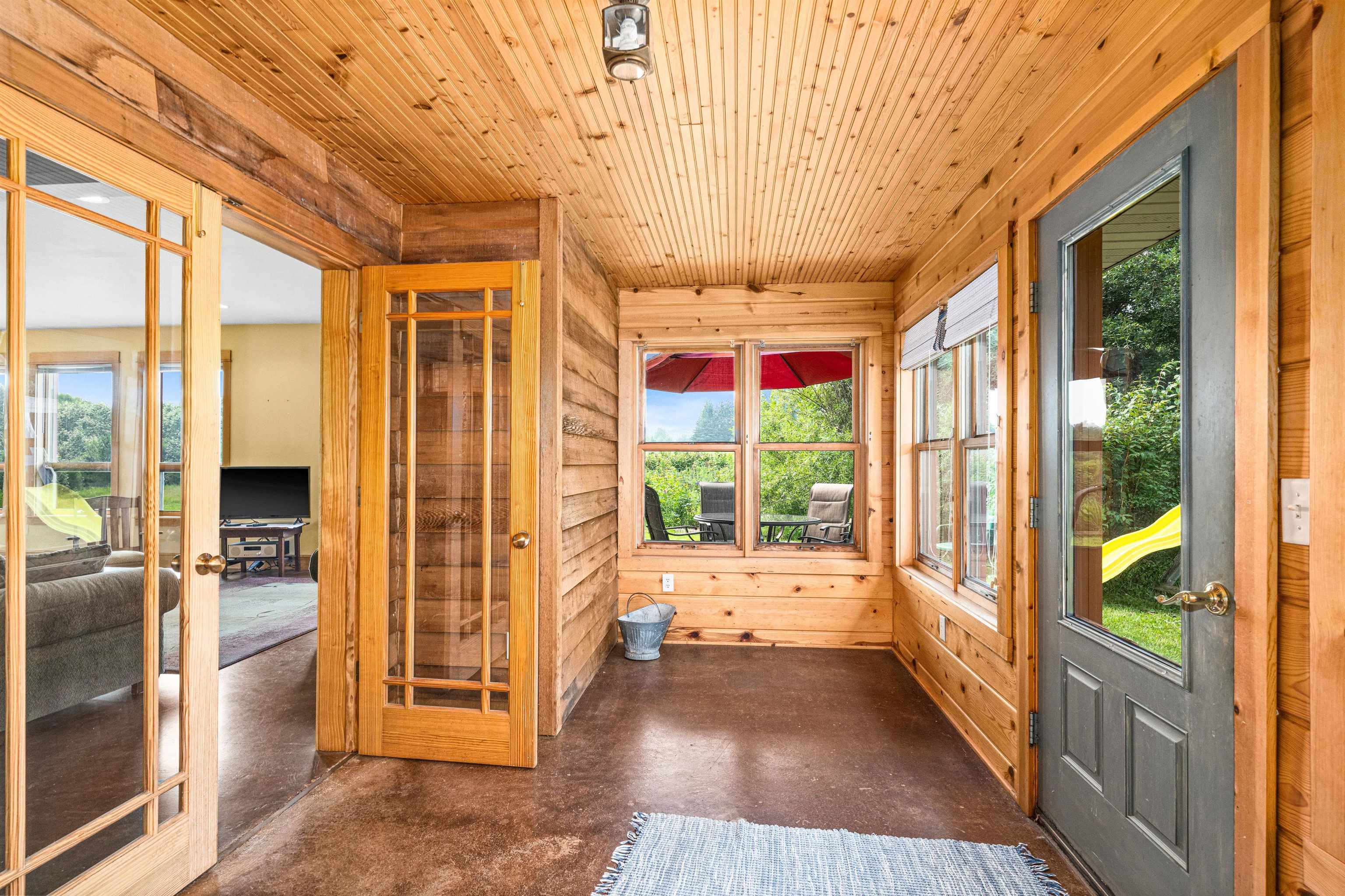 374 Nelson Road Cloquet, MN 55720 - Photo 14 of 33 Unfurnished sunroom featuring plenty of natural light, finished concrete flooring, wood walls, and wooden ceiling