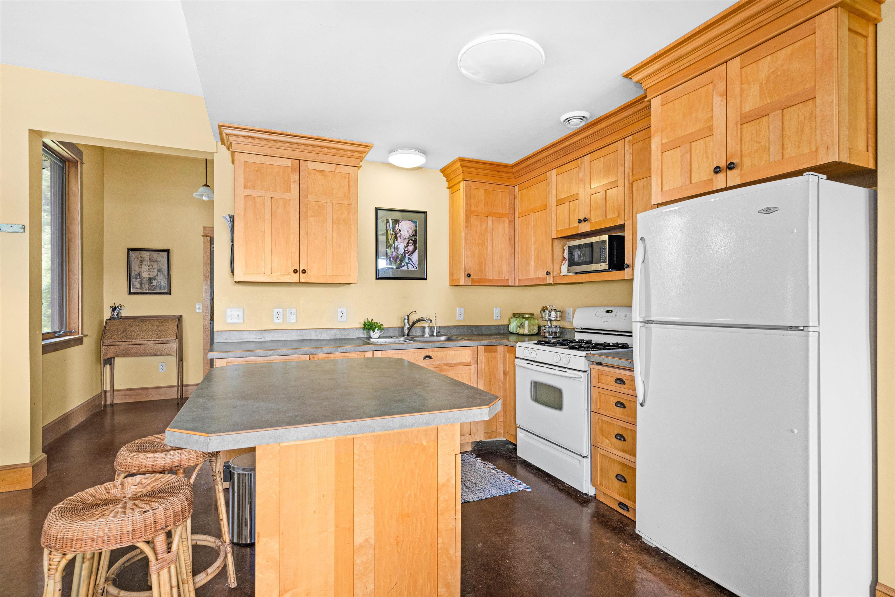 374 Nelson Road Cloquet, MN 55720 - Photo 15 of 33 Kitchen featuring white appliances, light brown cabinetry, a center island, and a breakfast bar area