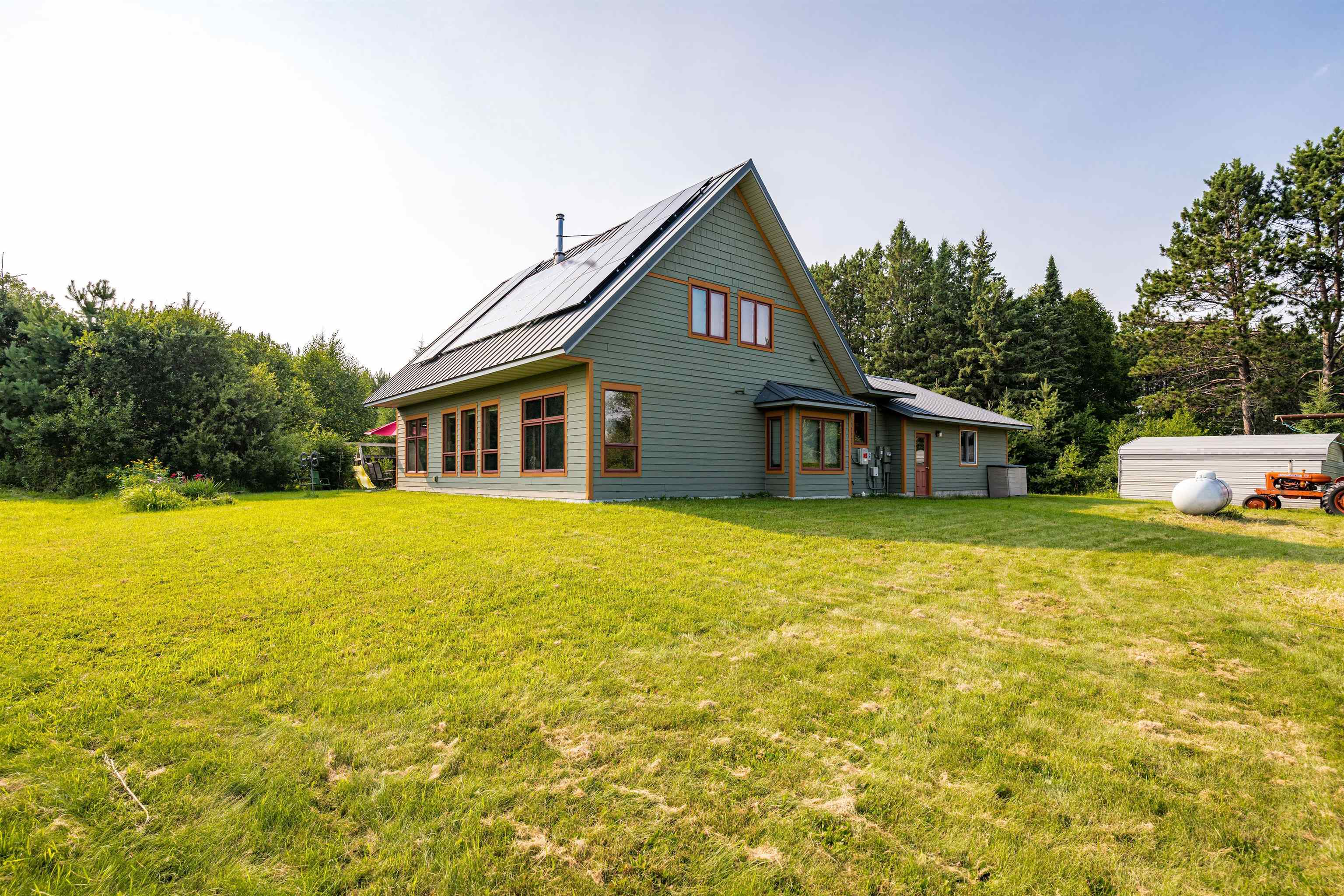 374 Nelson Road Cloquet, MN 55720 - Photo 4 of 33 Rear view of property featuring a yard, a metal roof, and roof mounted solar panels