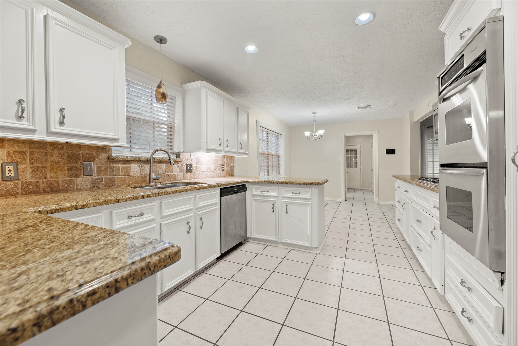 1103 Suwanee Lane Houston, TX 77090 - Photo 4 of 19 Step into this beautifully designed kitchen, featuring rich white cabinetry, granite countertops and coordinating backsplash.